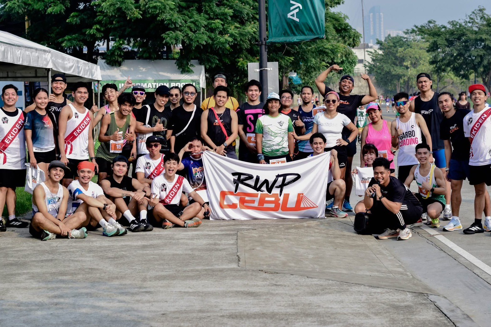 襷のメンバーと現地ランナーたちがRWP CEBUの旗を囲む集合写真